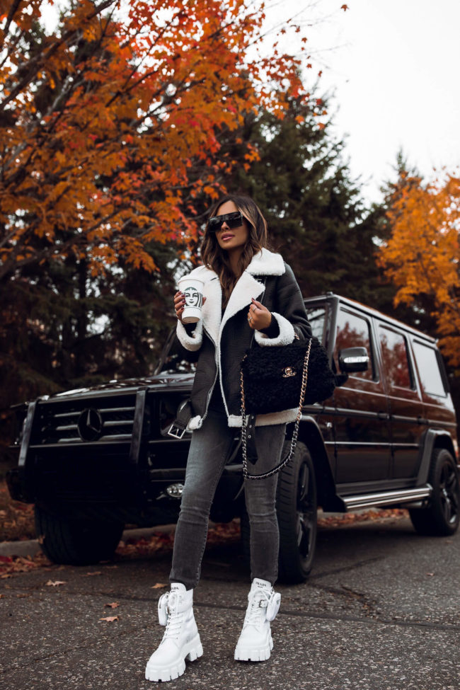fashion blogger wearing a shearling biker jacket from mango and prada monolith combat boots in white